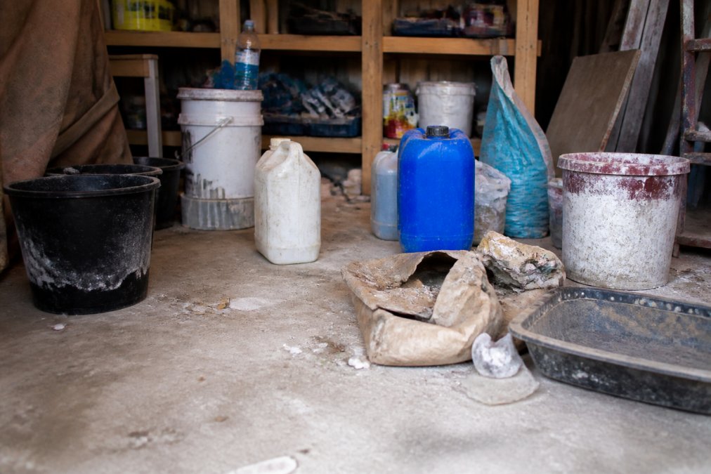 A contractor's hands carefully applying resin patch compound to a prepared driveway surface using a trowel, with proper spreading technique visible and cured resin sections in background