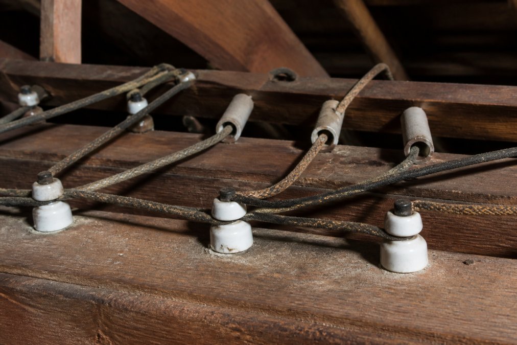 Diagram identifying components of knob and tube wiring with porcelain knobs and cloth-covered wires in joists