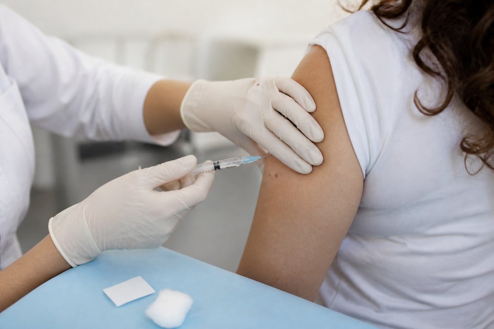 Professional demonstrating proper B12 injection technique with hands holding syringe, alcohol swab nearby, and injection site marked on upper arm in well-lit clinical setting