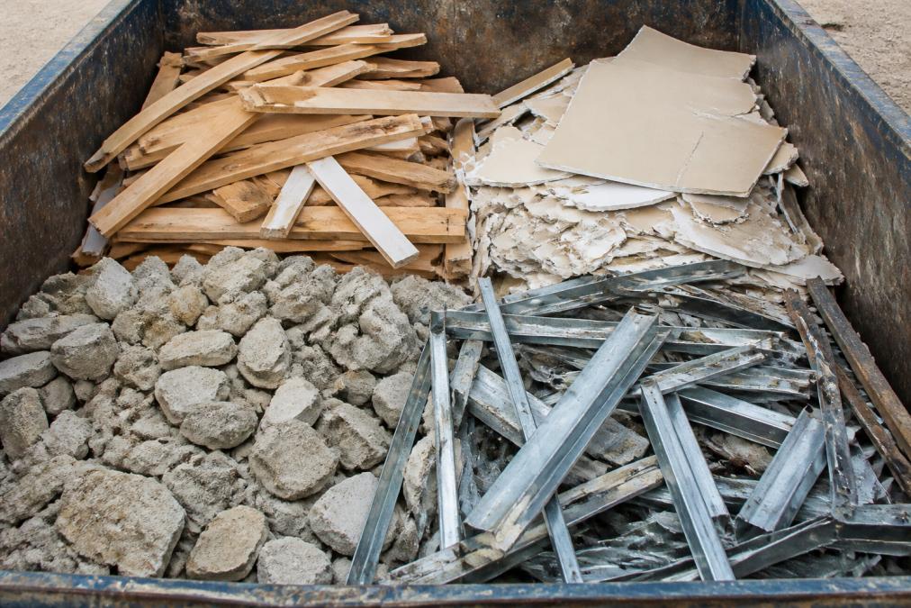 Close-up view of sorted construction debris inside a dumpster showing properly organized materials including wood, drywall, concrete, and metal demonstrating correct waste separation