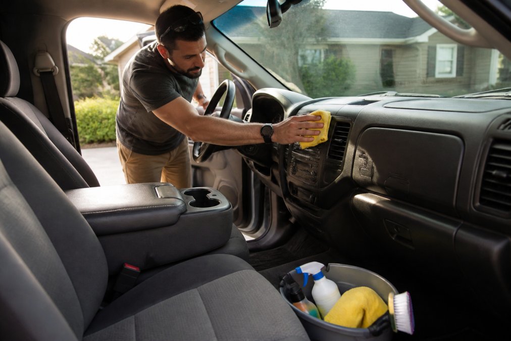 Person cleaning the dashboard of a pickup truck to help sell vehicle for cash effectively.