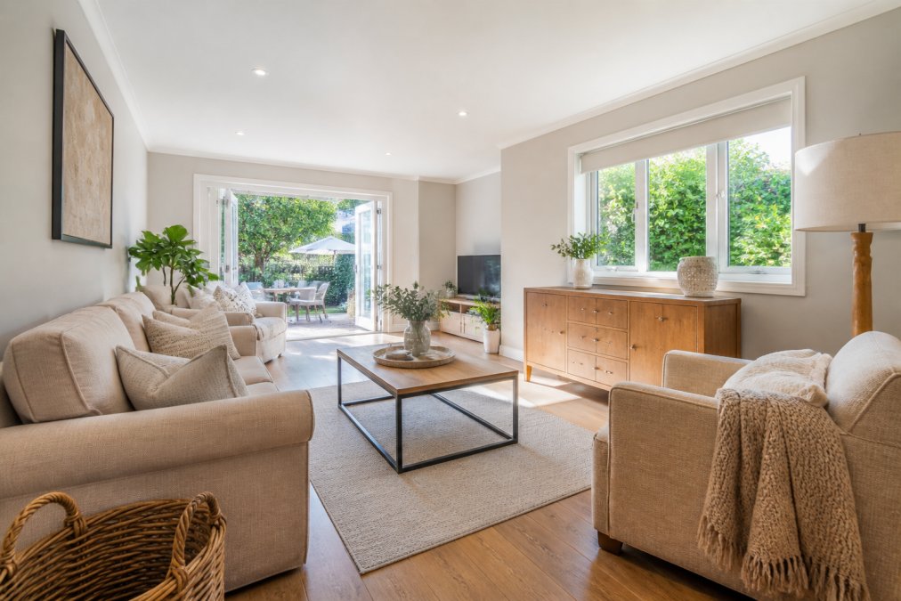 Bright, well-lit living room with decluttered furniture, neutral décor, and natural daylight streaming through windows, showcasing how professional staging enhances a property's appeal in photographs