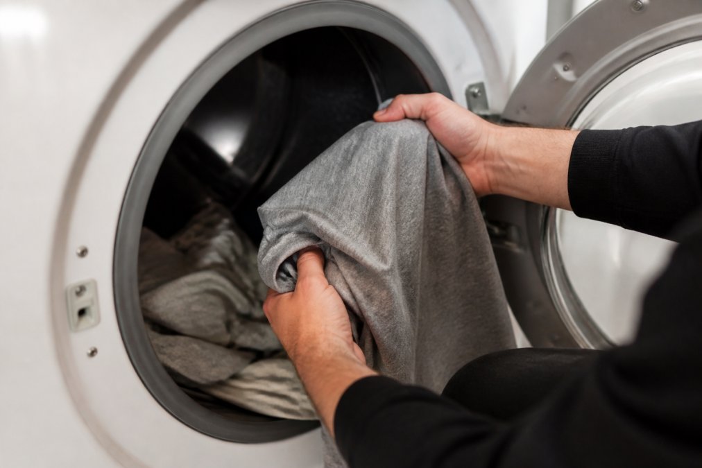 Close-up of hands turning a graphic t-shirt inside out before placing it in a dryer, showing the protective positioning of the printed design facing inward