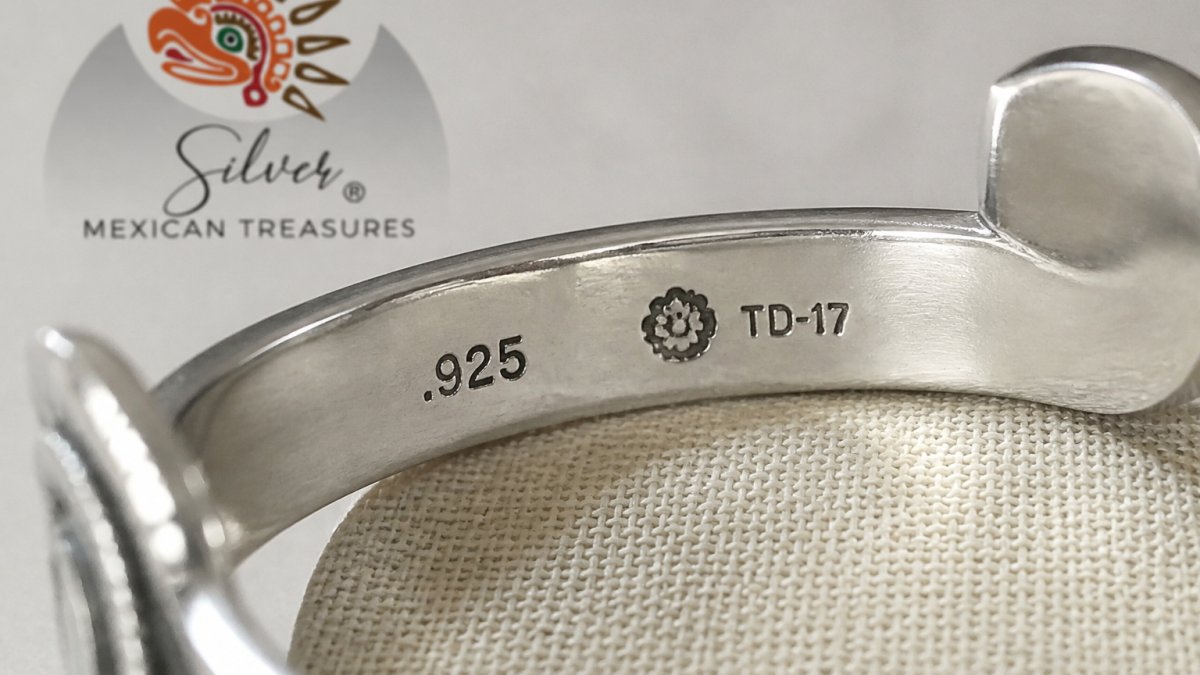 Close-up of sterling silver jewelry showing clear .925 hallmark stamp and maker's mark engraved on the metal surface, with natural diffused lighting highlighting the etched details