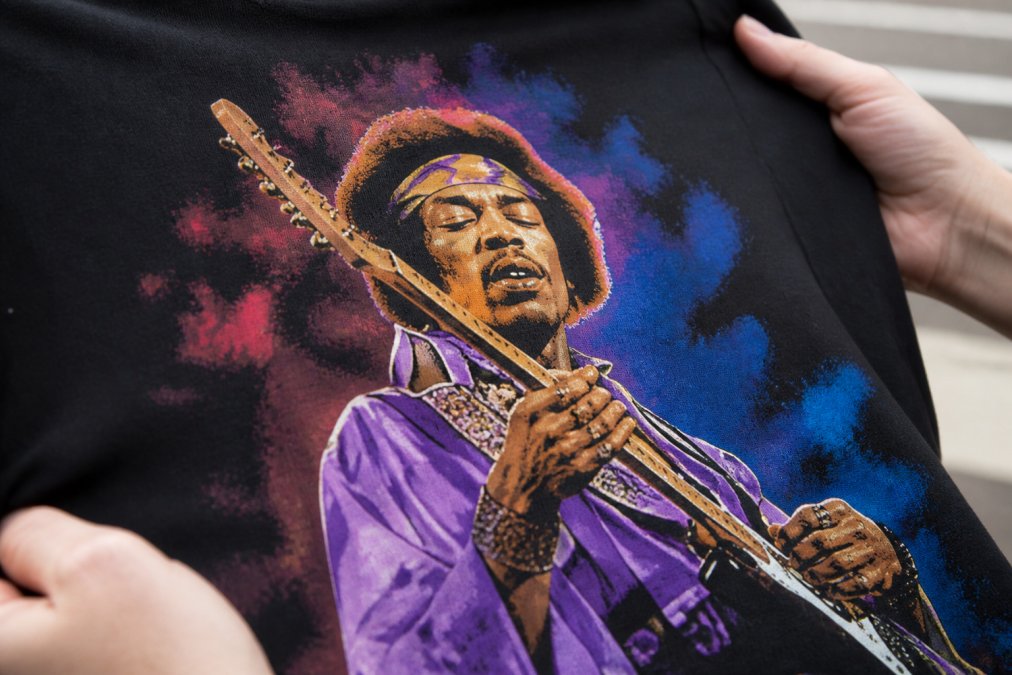 Close-up of a high-quality screen printed graphic tee showing crisp, sharp edges of a rock musician design with precise color boundaries and vibrant colors held under natural daylight