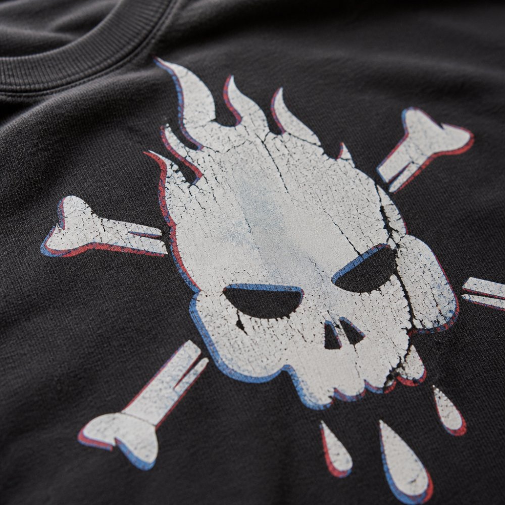 Close-up of a graphic tee showing common print defects including cracked and peeling ink edges, uneven color coverage with thin spots, and misaligned registration on the cotton fabric