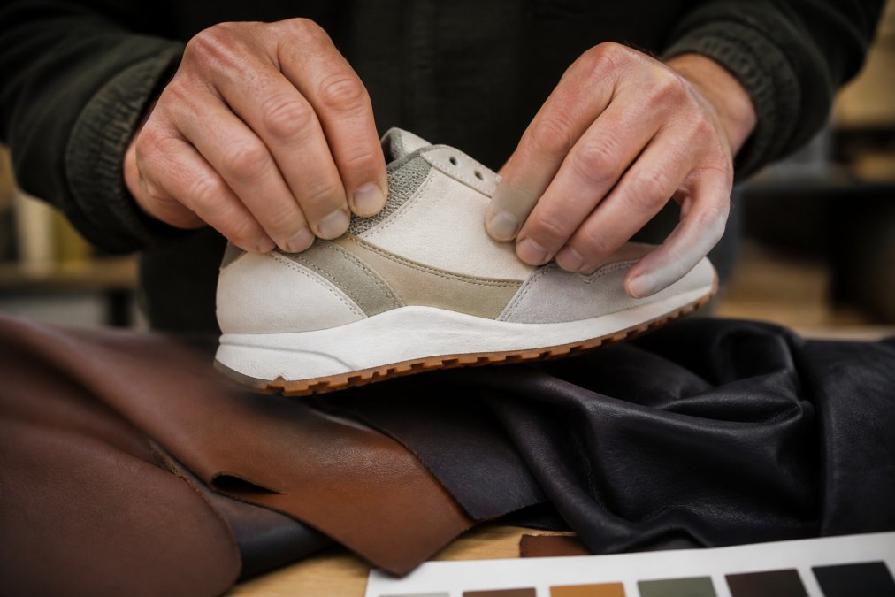 Close-up of hands carefully inspecting seams and materials on a product, examining construction details on a well-lit work surface with natural lighting
