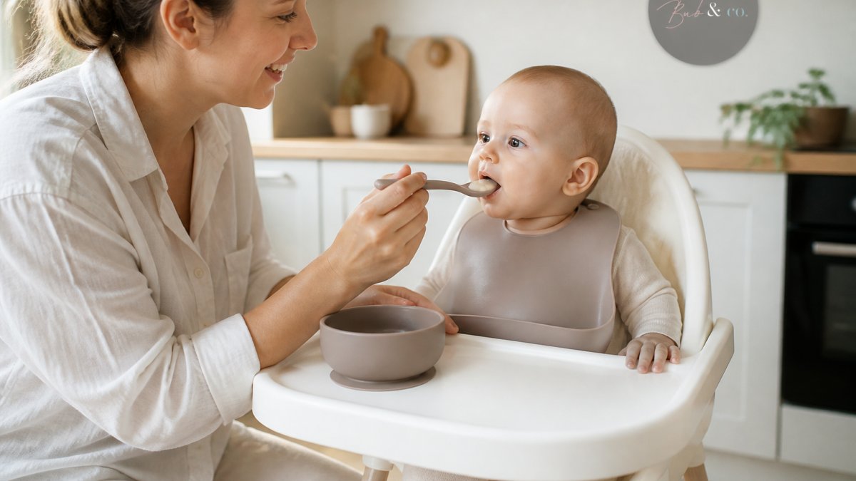 Parent feeding a calm baby in a highchair using a soft silicone spoon and suction bowl in a bright kitchen