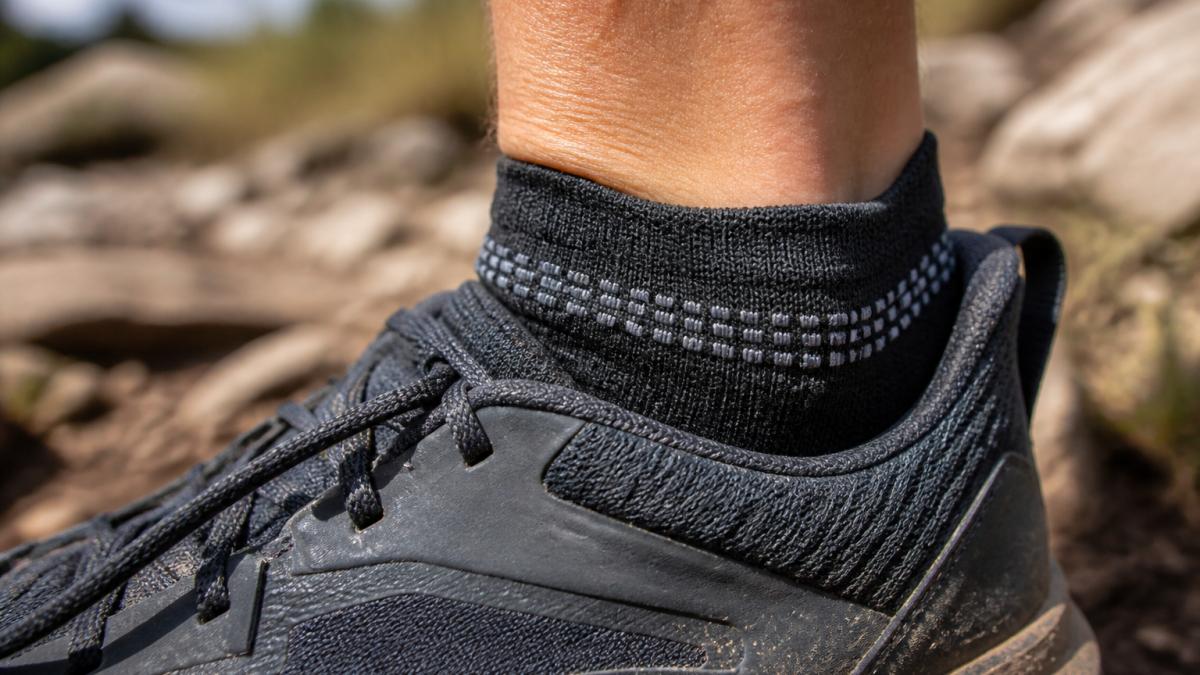 Diagram illustrating the placement of silicone heel grips on a sock to prevent slippage inside a trail running shoe.