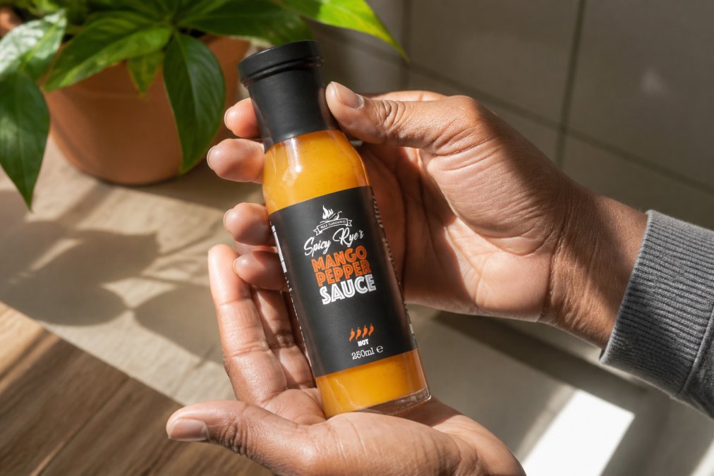 Hands holding a jar of hot sauce against natural light, showing colour clarity and consistency for inspection purposes
