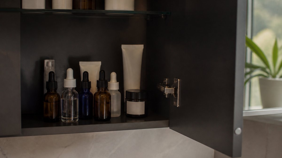 Copper peptide serum bottles stored in a cool, dark bathroom cabinet with the door slightly open, showing proper placement away from direct sunlight and heat sources