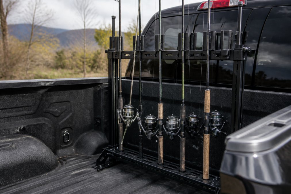Fishing rods secured vertically in a truck bed rack system, showing rods standing upright with rod tips protected and reels visible from the side