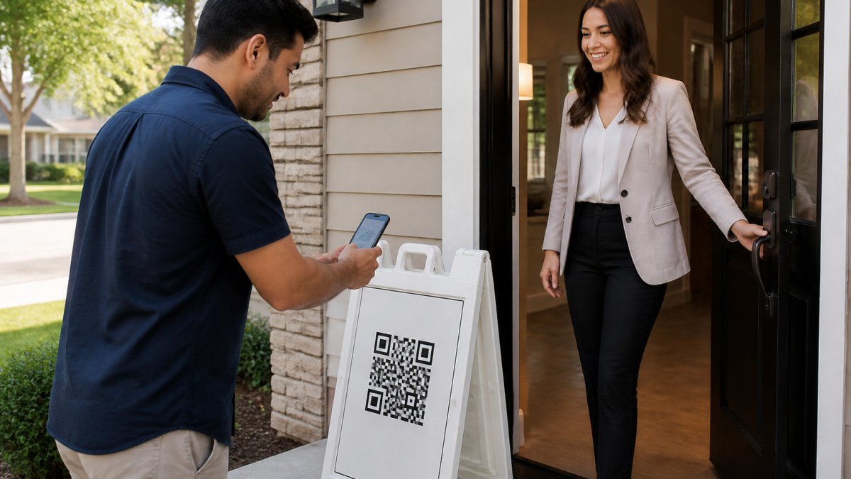 Real estate agent in professional attire standing at home entrance, greeting a visitor who is scanning a QR code on their smartphone, with a branded QR sign visible on a white a-frame stand beside them, natural daylight