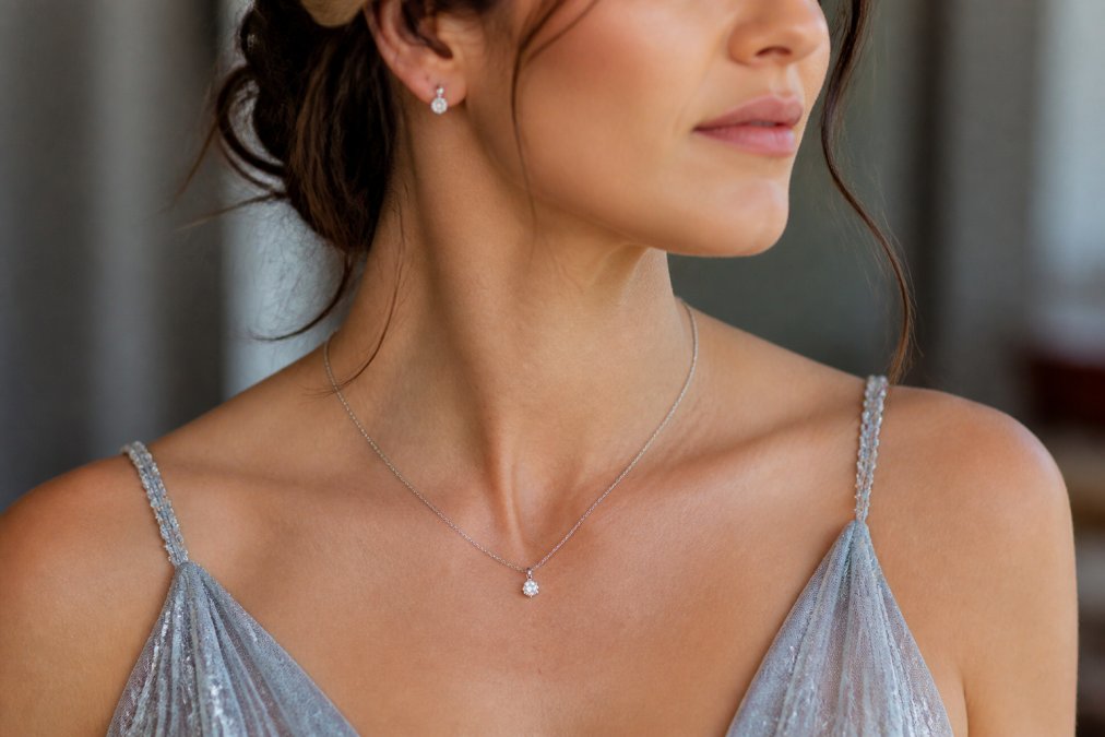 Delicate pendant necklace and small earrings paired with a formal wedding dress neckline to style accessories.