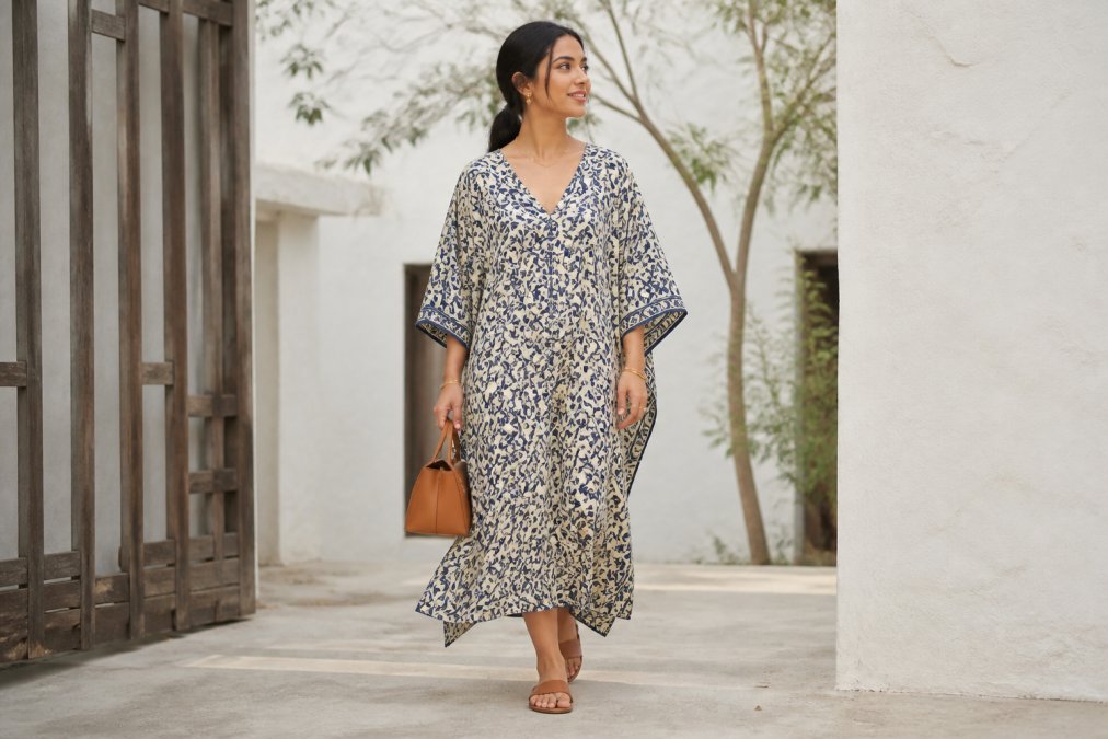 Woman wearing a bold hand block printed kaftan styled with minimal gold jewellery, neutral leather sandals, and a simple structured bag, demonstrating balanced accessorising for a statement print