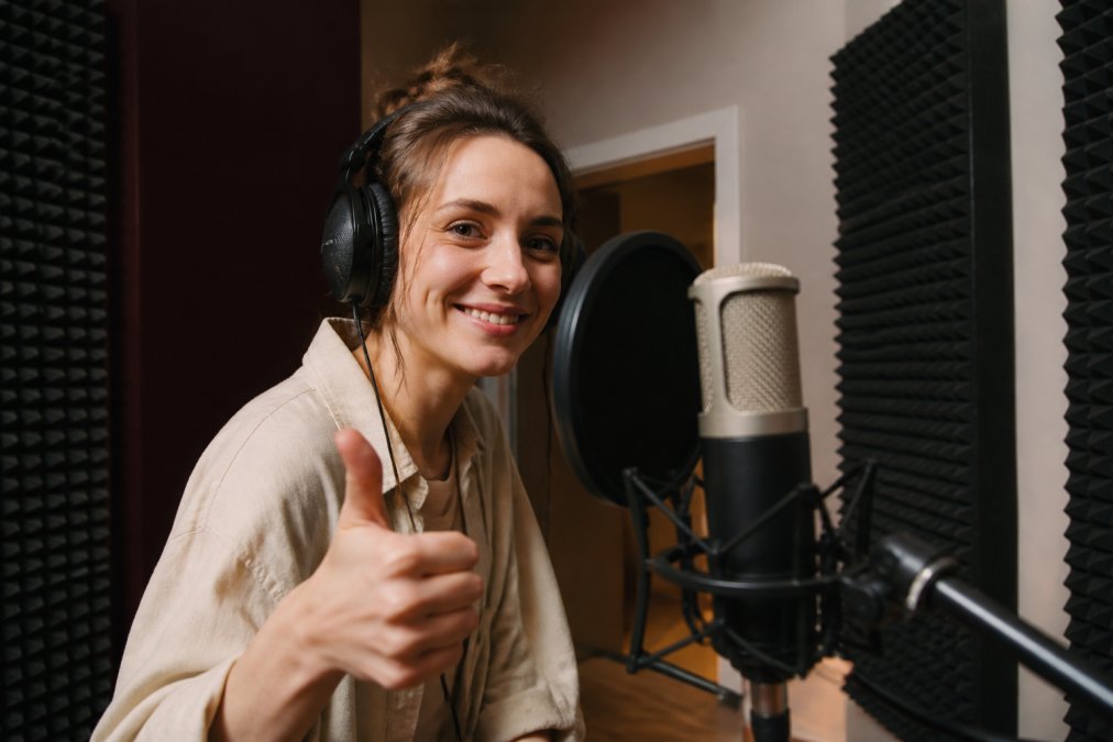 Voice actor in a home studio giving a thumbs up to support independent voice actors during a remote recording session.