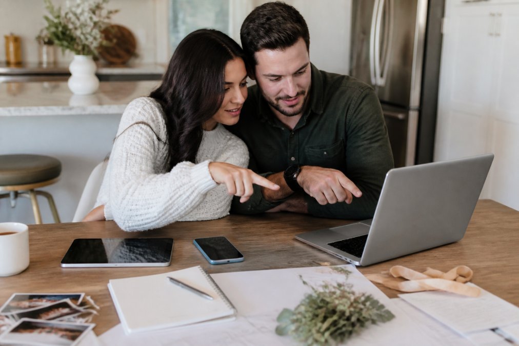 Couple using a laptop, tablet, and smartphone to learn how to sync shared wedding documents together