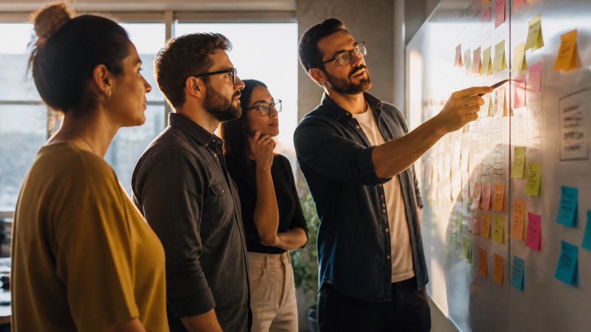 How to Systematize Agency Operations Step by Step Team members collaborating on a whiteboard to systematize agency operations with workflow diagrams.