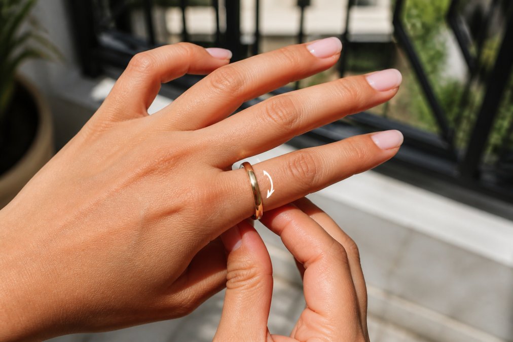 Close-up of a hand demonstrating ring spinning motion on the finger, showing the rotation and visible gap between the band and skin in natural daylight