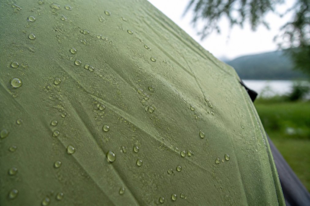 Water droplets beading on a DWR-coated fabric to show the tent is waterproof under natural daylight.