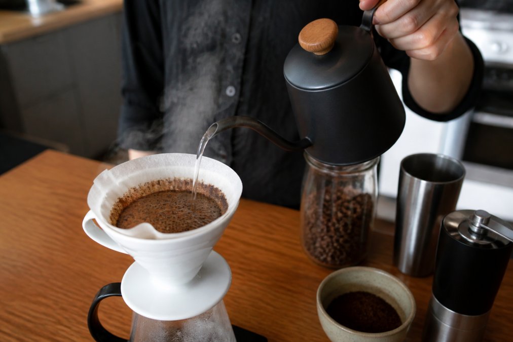 Hands pouring hot water over fresh coffee grounds to see the bloom, a key way how to tell if coffee beans are fresh.