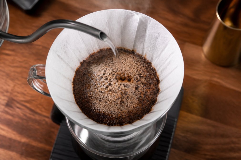 Hot water pouring over ground coffee causing a bubbling bloom to show how to tell if coffee is fresh roasted