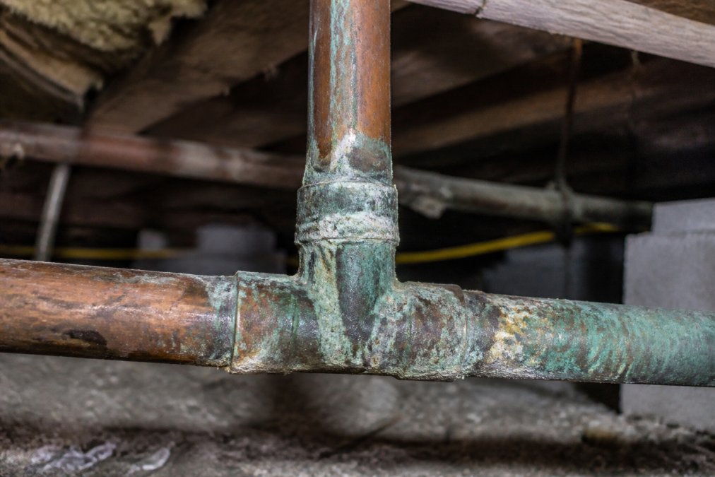 Infographic visualizing signs that pipes are failing through green oxidation and mineral buildup on copper.