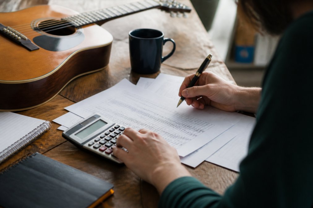Independent label manager reviewing artist royalty statements and payment records at a desk