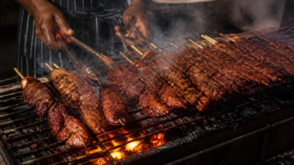 Chef using tongs to turn meat skewers over glowing embers for an authentic open fire cooking taste