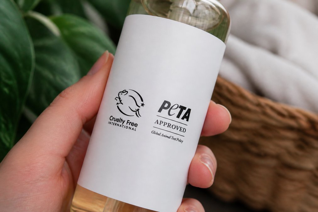 Close-up of skincare product packaging displaying official cruelty-free certification seals including Leaping Bunny logo and PETA certified mark on white label with natural product visible