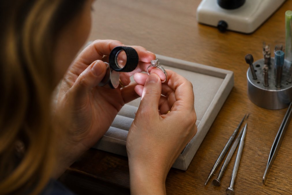 Jeweler using a magnifying loupe to inspect the prong settings and security of a diamond engagement ring