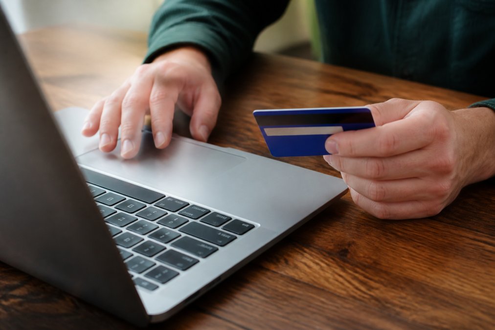 Hands entering payment information on a secure checkout page with visible trust badges and SSL padlock indicator displayed on the screen