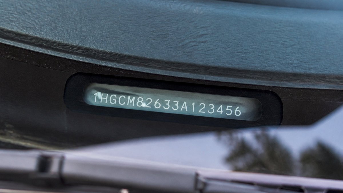Close-up of a VIN plate on a vehicle dashboard showing the 17-character identification number with natural lighting and clear digit visibility