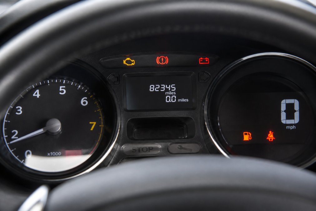 Close-up of a car's digital odometer and instrument cluster showing mileage display with dashboard warning lights visible