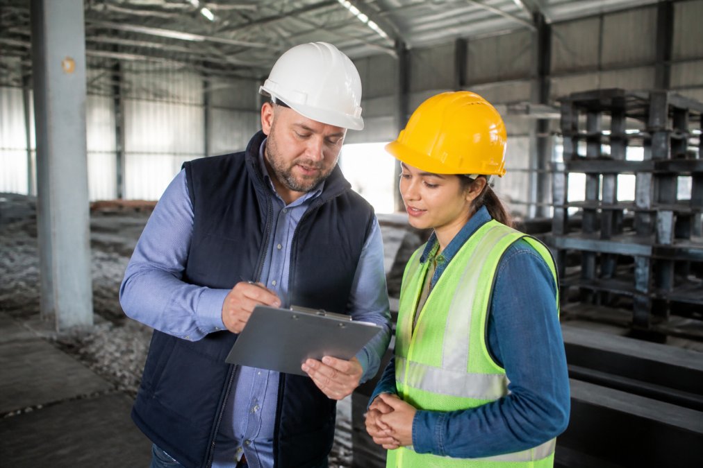Manager and temporary worker having a constructive conversation on a job site, reviewing performance feedback and discussing expectations, natural workplace lighting