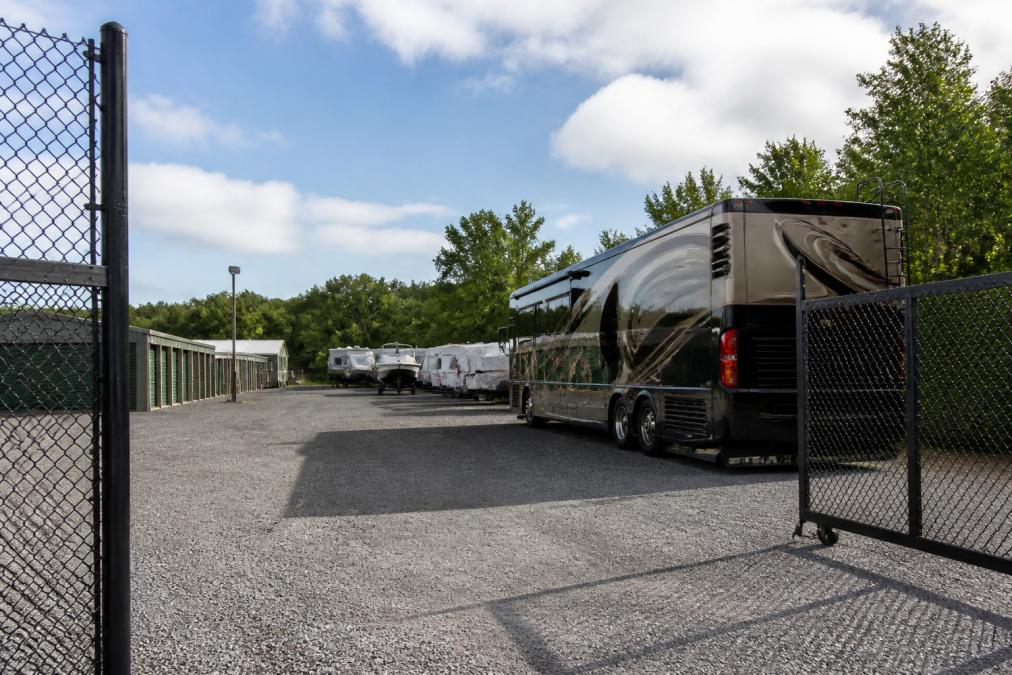 Large RV parked in secure outdoor storage facility with gated fencing, clear access lanes, and ample space between vehicles