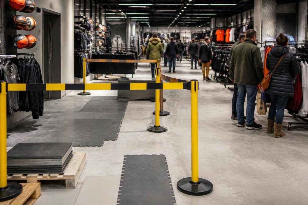 En butik under renovering med nye gulvbelægninger, butikken er åben med kunderne handlende, installationsområdet er afspærret med signering og barrierer