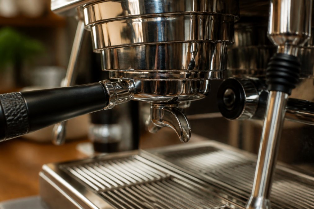 Detaljeret nærbillede af højkvalitets kaffemaskines metalkomponenter - poleret rustfrit stål, præcisionsvindinger og håndværksmæssigt designede detaljer under varmt naturligt lys