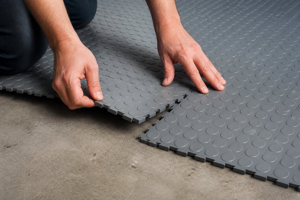 Hvorfor vælge PVC-fliser til garage 2 Tæt optagelse af hænder, der forbinder PVC-garagegulvfliser sammen ved hjælp af kliksystemet, hvilket viser sammenlåsningsmekanismen i aktion