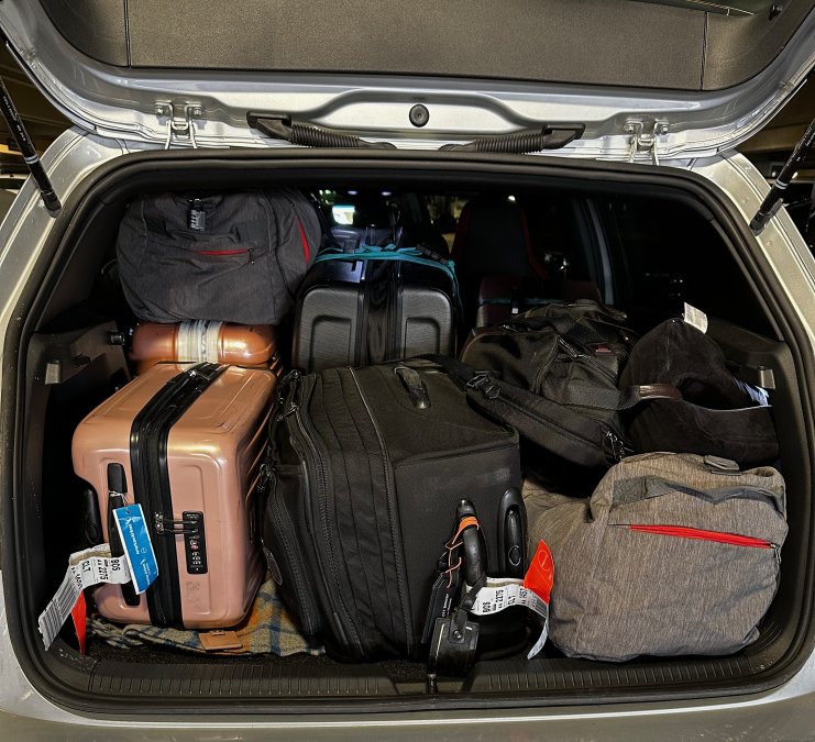 back of hatchback full of suitcases and duffle bags