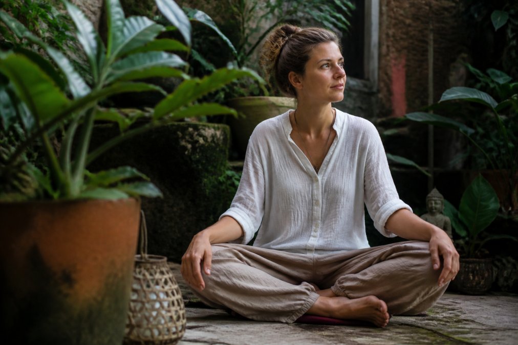 Person in ruhiger Meditationsumgebung, von Pflanzen und Natur umgeben, nachdenklicher Ausdruck, die innere Verarbeitung und psychologische Heilung nach einer Iboga-Erfahrung andeutend