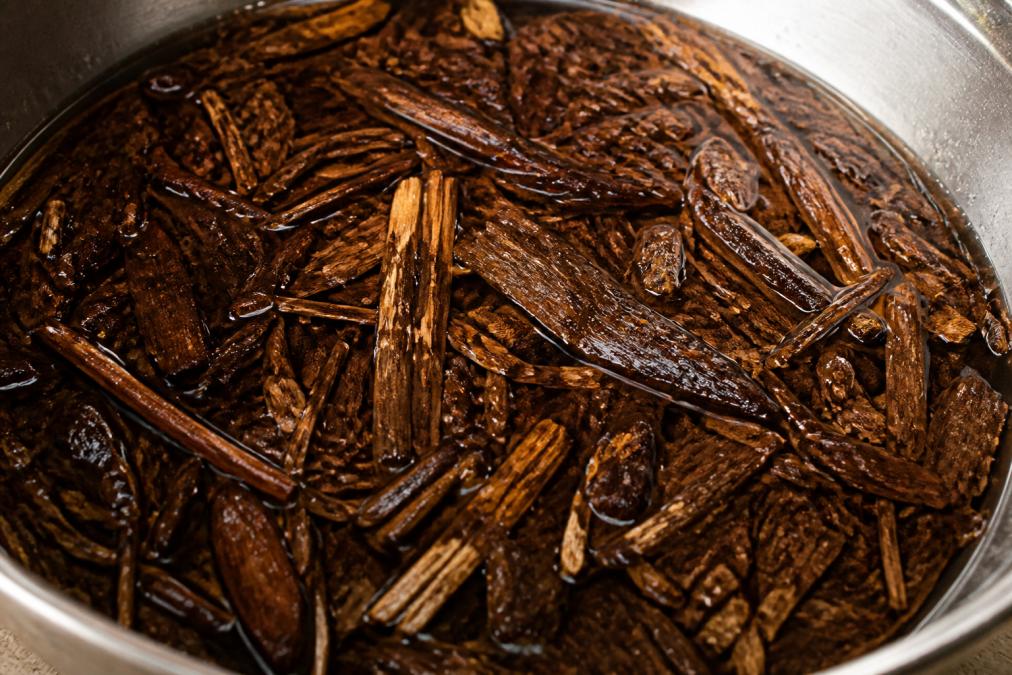 Detaillierte Nahaufnahme von Iboga-Wurzelrinde in einer Schale mit Wasser, zeigt die physische Form des Produkts vor der Anwendung und Vorbereitung