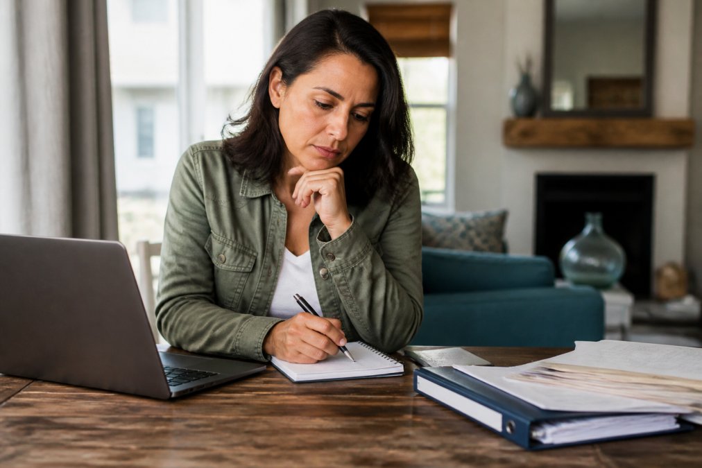 Person reviewing paperwork and taking notes on an identity cleanup mortgage recovery plan at a desk