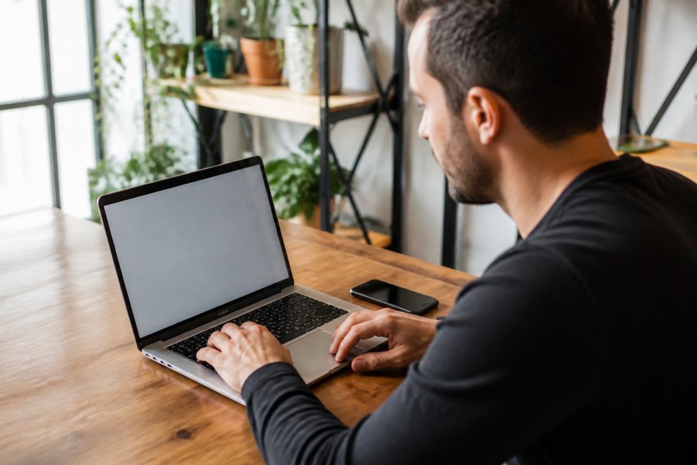 Small business owner at desk reviewing Google Business Profile on laptop screen with verification checkmark and business information displayed