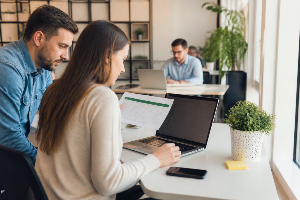Marketing professional uploading conversion data to a laptop to improve lead quality in a modern office