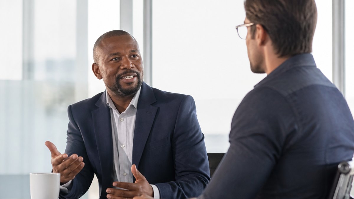 Manager having a genuine conversation with an employee to improve team engagement in a modern office.