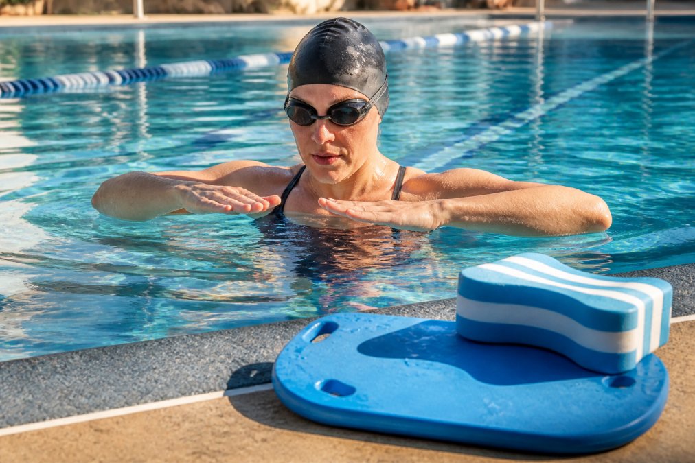 Adult triathlete practicing a sculling drill in a lap pool to improve swimming technique