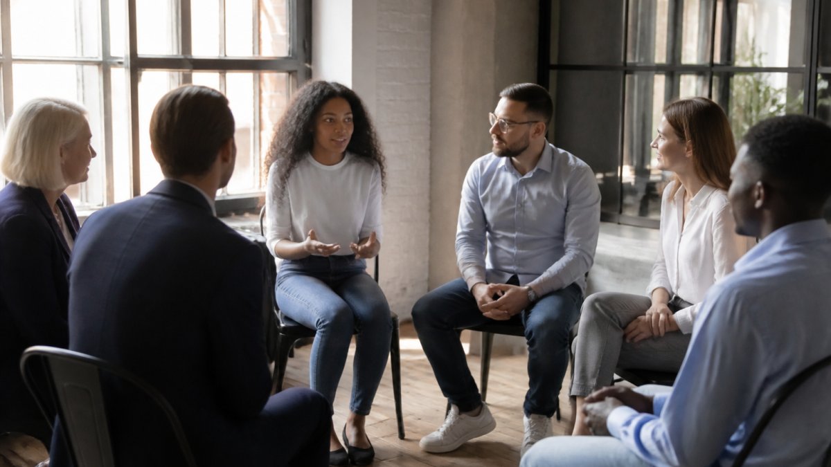Diverse professionals sitting in a circle, improving team engagement with communication through trust-building exercises.