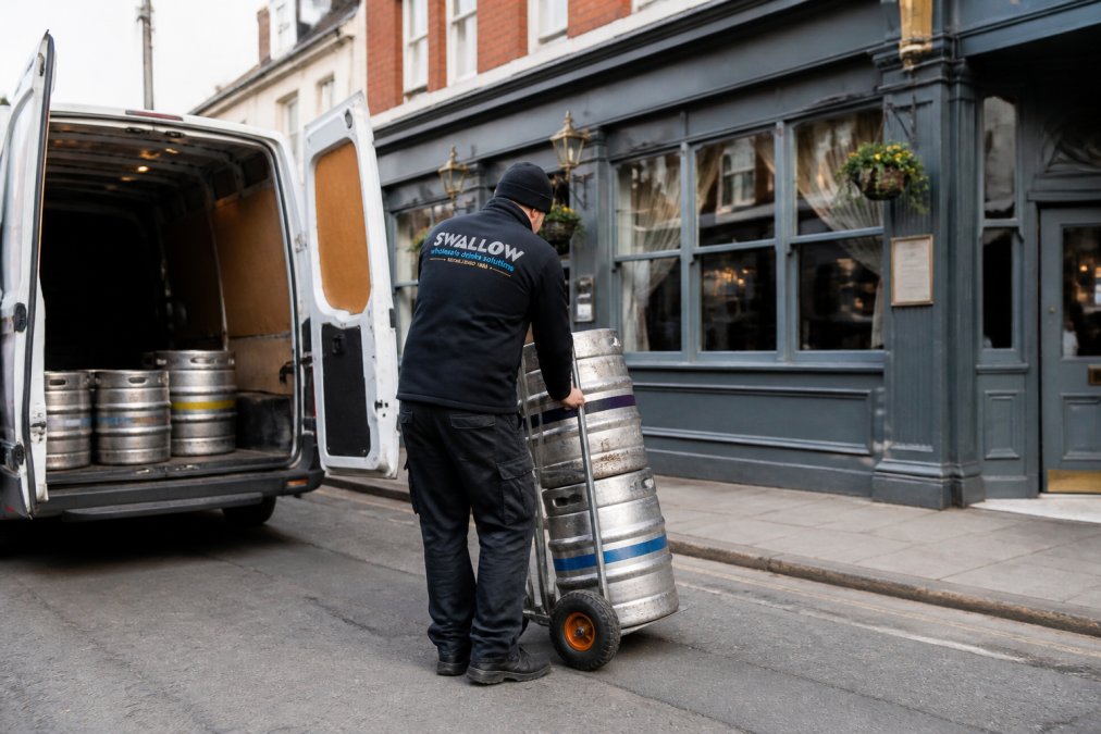 Delivery driver unloading beer kegs from a van at a Birmingham pub