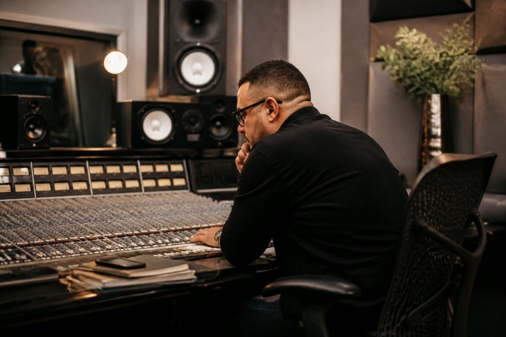 Music producer or label manager reviewing streaming analytics and platform data on multiple monitors in a professional studio or office environment, with detailed dashboards visible